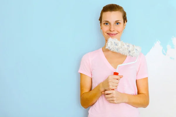 Happy Woman standing againtst wall with roller brush. — Stock Photo, Image