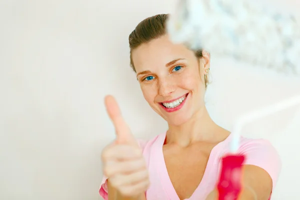 Happy Woman showing thumb up with roller brush. — Stock Photo, Image