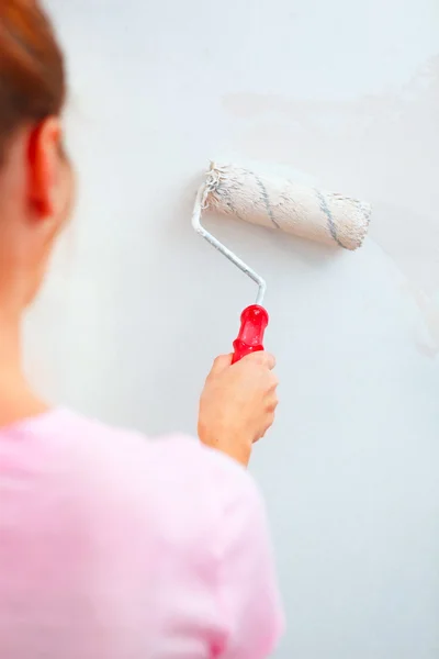 Junge Frau bemalt Wand mit Rollerpinsel. — Stockfoto