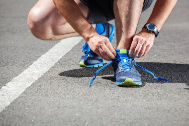 Koşucu koşu ayakkabılarını deniyor koşuya hazırlanıyor.