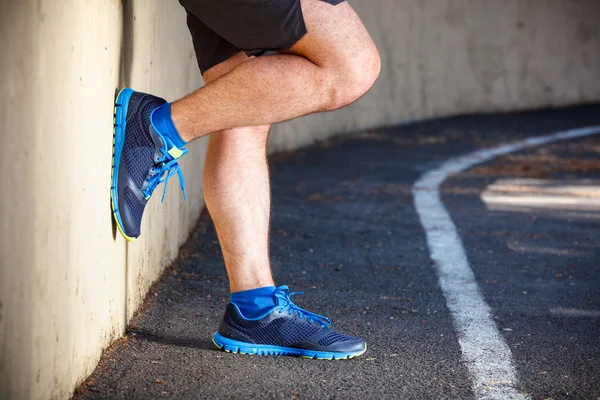 Male runner leaning relaxed against wall. — Stock Photo, Image