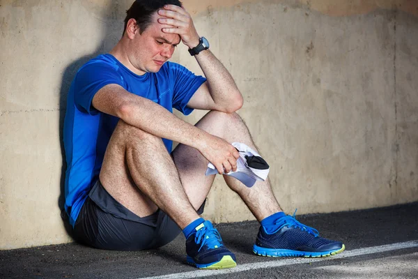 Boos jonge mannelijke atleet rusten leunend tegen muur. — Stockfoto