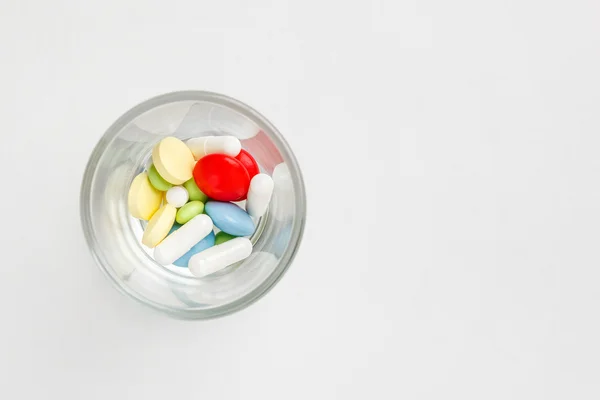 Vele kleurrijke pillen en tabletten in glas. — Stockfoto