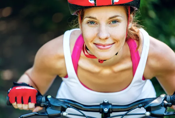 Gelukkig jonge vrouw leunde over het stuur van haar fiets. — Stockfoto