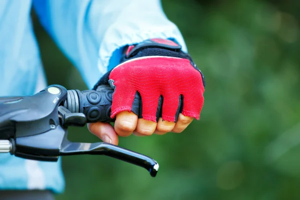 Close-up van handen in rode beschermende handschoenen houden Stuur. — Stockfoto