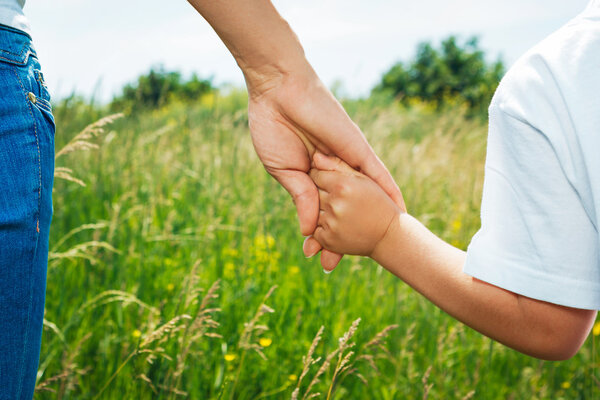 Mother holding hand of her son outdoors