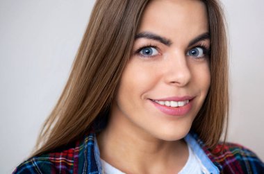 Duvara poz ekose gömlekli mutlu genç kadın portresi stüdyo.