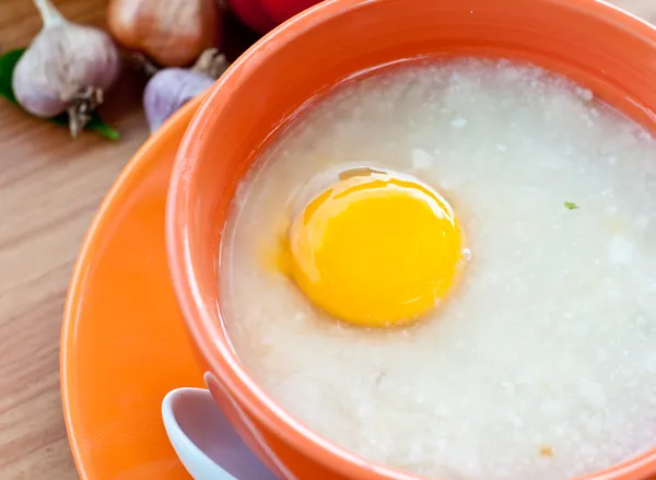 Rice porridge with egg in orange bowl. — Stock Photo, Image