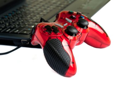 Kırmızı joystick oyun kumandası üstünde laptop .