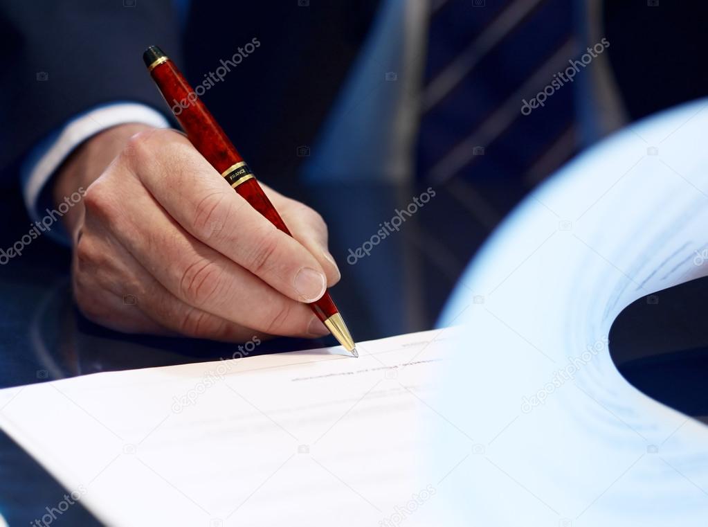 Close up of businessman signing a contract.