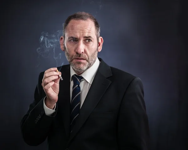 Mature businessman smoking a cigarette — Stock Photo, Image