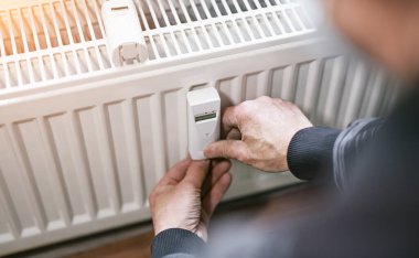 Isıtma sistemi mühendisi yeni bir termal radyatörün dijital w-lan ağ termometre okuyucusunu ayarlıyor.