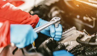 Auto mechanic working on car engine in mechanics garage. Repair service. authentic close-up shot - selective focus