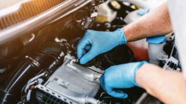 Auto mechanic working on car engine in mechanics garage. Repair service. authentic close-up shot - selective focus
