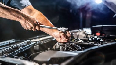 Auto mechanic working on car engine in mechanics garage. Repair service. authentic close-up shot - selective focus with motion blur