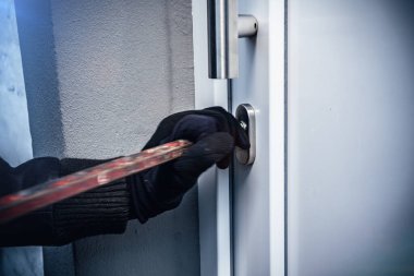 masked burglar with crowbar breaking and entering into a victim's home. motion blur selective focus