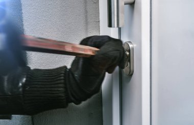 masked burglar with crowbar breaking and entering into a victim's home. motion blur selective focus
