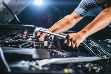 Auto mechanic working on car engine in mechanics garage. Repair service. authentic close-up shot - selective focus with motion blur