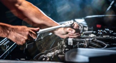 Auto mechanic working on car engine in mechanics garage. Repair service. authentic close-up shot - selective focus with motion blur