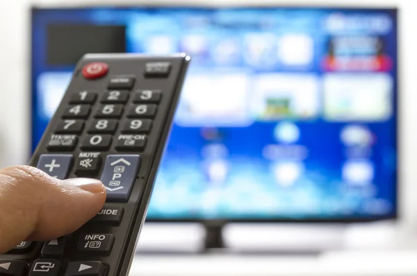 Smart tv and hand pressing remote control — Stock Photo, Image