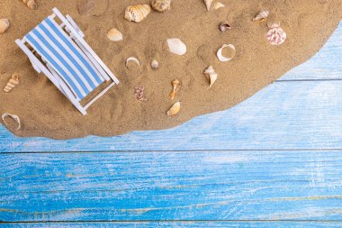 Mavi bir arka planda, kumdaki deniz kabukları ve güneş ışığı. Yaz tatili, plaj, rahatlama, deniz, okyanus, seyahat konsepti.