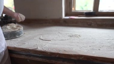 Fırıncı ekmek için hamur yoğurmadan önce masayı un döktü.