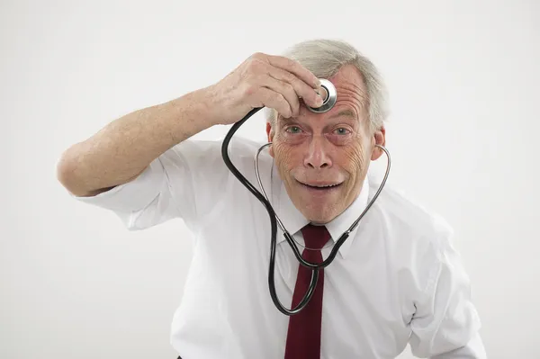 Starší muž, který držel stethosope na čelo — Stock fotografie