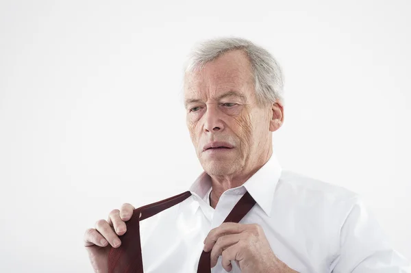 Elderly man putting on his tie — Stock Photo, Image