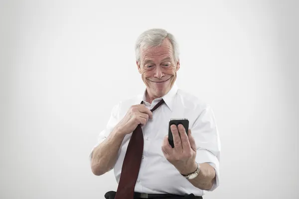 Старший мужчина улыбается на мобильный телефон — стоковое фото