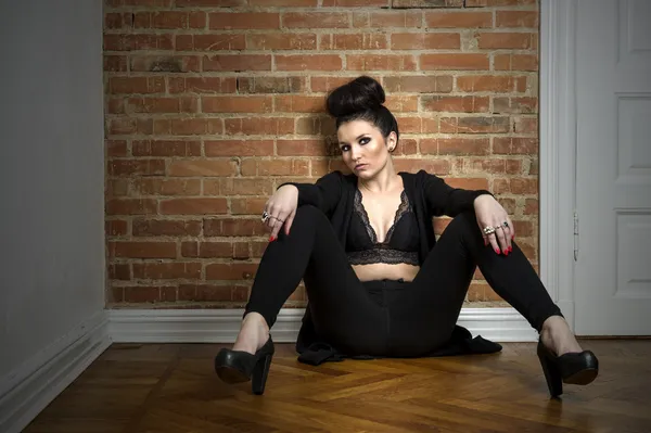 Moody elegant woman sitting on a parquet floor — Stock Photo, Image