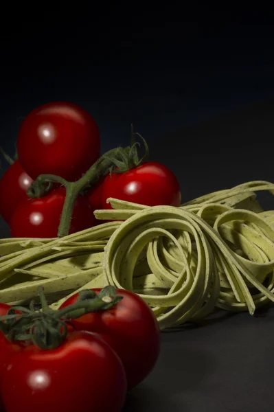 Torkade tagliatelle pasta och mogna körsbärstomater — Stockfoto