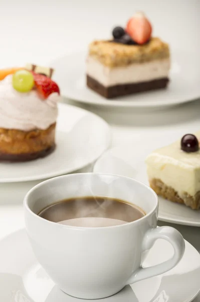 Hot fresh cup of coffee with a variety of cakes — Stock Photo, Image