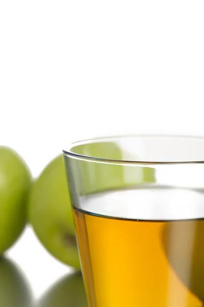 Glass filled with juice in front of apples — Stock Photo, Image