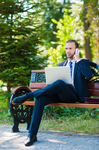 Giovane uomo d'affari che lavora con laptop e cellulare — Foto Stock