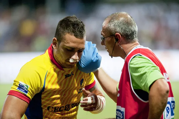 El médico que proporciona primeros auxilios al jugador de rugby lesionado — Foto de Stock