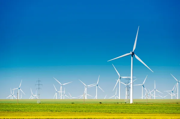 Ветряные мельницы для генерации энергии ветра с голубым небом и зеленым лугом — стоковое фото
