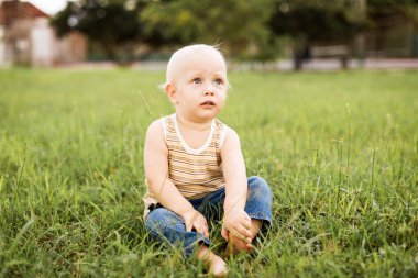 Yeşil çimenlerin üzerinde oturan erkek bebek