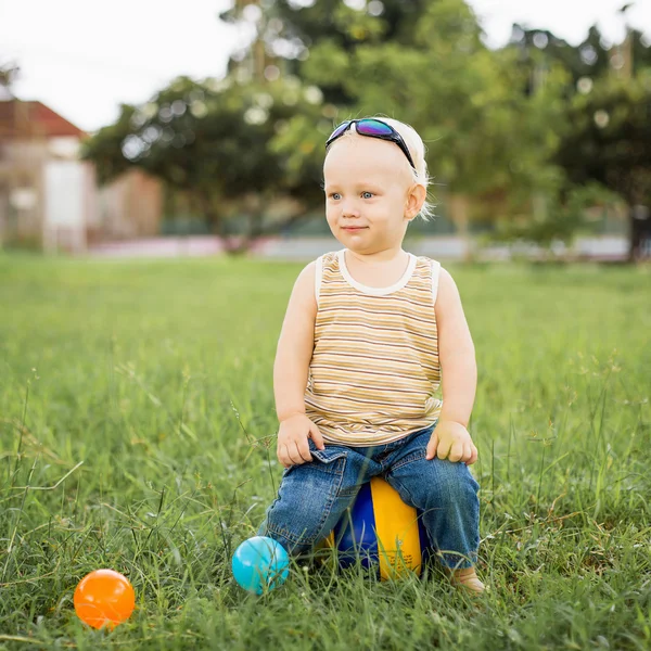 Chłopiec siedzi na zielonej trawie — Zdjęcie stockowe