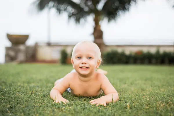 Niño en un césped verde —  Fotos de Stock