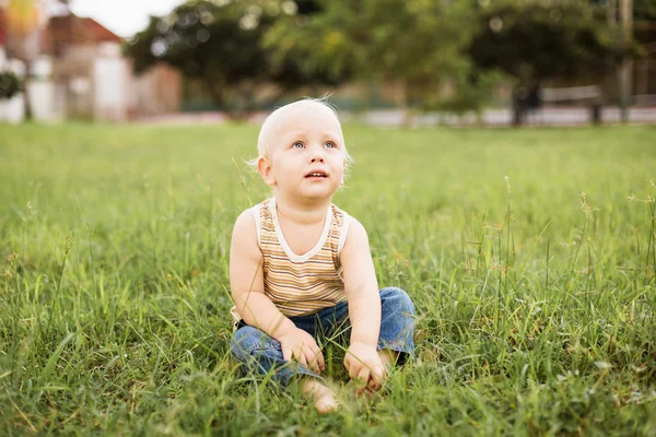 Lille gutt som sitter på det grønne gresset – stockfoto
