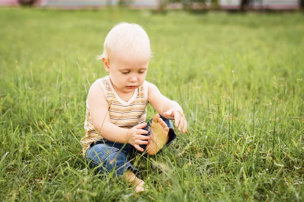 Petit garçon assis sur l'herbe verte — Photo