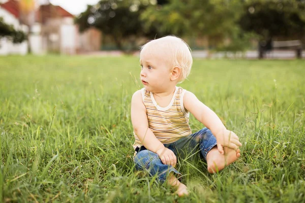 Yeşil çimenlerin üzerinde oturan erkek bebek — Stok fotoğraf