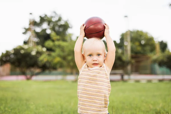 Pequeño niño sosteniendo una pelota sobre su cabeza — Foto de Stock