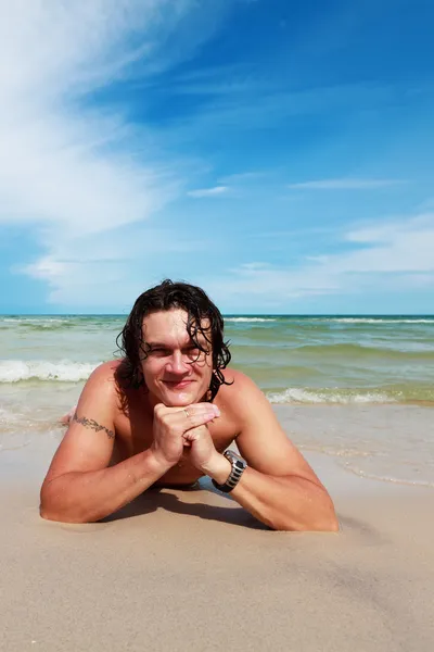 Un jeune homme allongé au bord de la mer — Photo