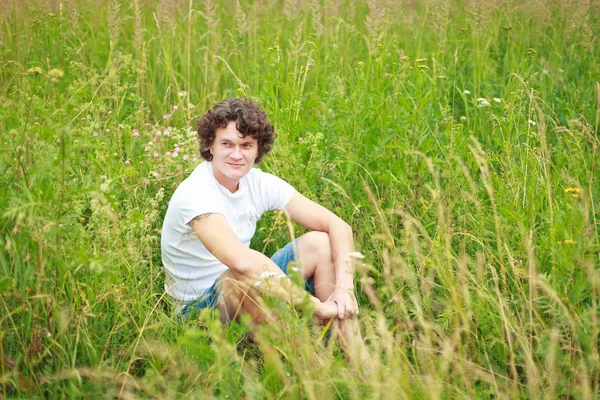 Un jeune homme assis sur l'herbe — Photo