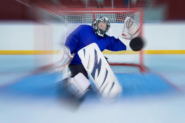 Junger Eishockey-Goalie fängt einen fliegenden Puck Stockfoto