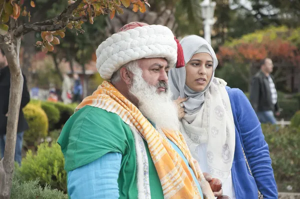 ISTANBUL,TURKEY - JULY 15: Man impersonating the legendary Turkish folkloric comedy character Nasreddin Hodja with unidentified tourists posing for memory photos in Istanbul on July 15, 2014 — Stock Photo, Image