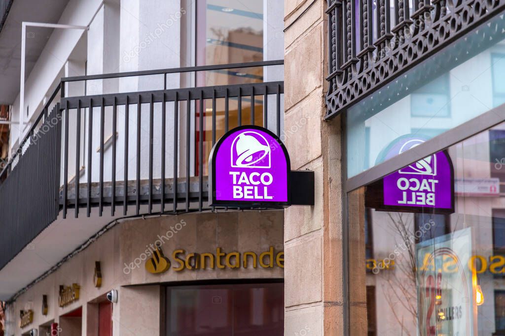 Seville, Spain-FEB 24, 2022: The entrance and the signboard with logo of Taco Bell in Seville, Spain. American chain of fast food restaurants originating in Irvine, California.