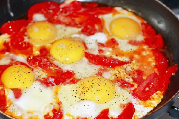 Ovos fritos com tomate em uma frigideira — Fotografia de Stock