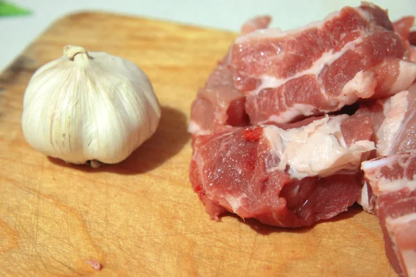 Carne fresca e alho fresco deitado na mesa da cozinha — Fotografia de Stock